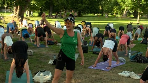 Eine Yogalehrerin und ihr Kurs in einem Park. Raha Bamdadi macht seit drei Jahren den Kurs "Yoga auf Englisch". Zum Kurs in die Ulmer Friedrichsau kommen oft mehr als 100 Teilnehmende.