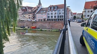 Rettungskräfte der DLRG, der Wasserwacht und der Polizei sind an der Donau in Ulm im Einsatz. Sie suchen einen vermissten Mann. 