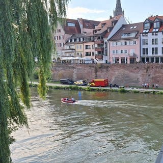 Rettungskräfte der DLRG, der Wasserwacht und der Polizei sind an der Donau in Ulm im Einsatz. Sie suchen einen vermissten Mann. 