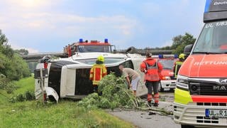 Auto liegt start beschädigt auf dem Seitenstreifen der Autobahn. Feuerwehr ist vor Ort.