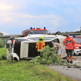 Auto liegt start beschädigt auf dem Seitenstreifen der Autobahn. Feuerwehr ist vor Ort.