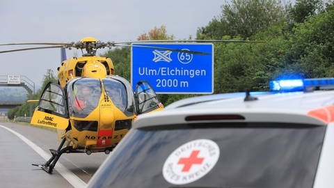 Rettungshubschrauber steht auf der Autobahn A8 direkt vor dem Schild 2.000 Meter bis Autobahnkreusz UlmElchingen.