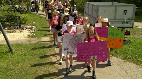 Kinder und Eltern mit Schildern bei einer Demonstration für einen Ponyclub. Moralische Unterstützung: Eltern und Kinder sind auf den Ponyhof gekommen, um in einer spontanen Demonstration für den Erhalt des Betriebs am Standort Lauchheim einzustehen.