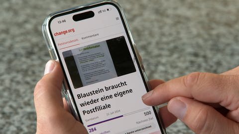 Eine Petition mit dem Titel "Blaustein braucht wieder eine eigene Postfiliale" ist auf einem Handybildschirm zu sehen.