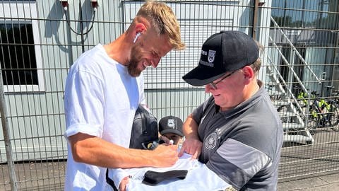 Johannes Reichert vom SSV Ulm 1846 Fußball unterschreibt auf dem Trikot eines Fans vor dem Donnaustadion. Vor dem Pokalspiel gegen Bayern München sind die Ulmer Spieler gefragt.