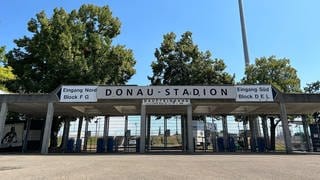 Der Haupteingang zum Ulmer Donaustadion. Im Hintergrund ein Flutlicht. Am Freitagabend steigt hier das Pokalspiel SSV Ulm 1846 Fußball gegen Bayern München.