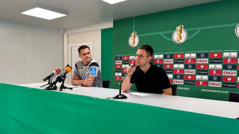 SSV Ulm 1846 Fußball Cheftrainer Thomas Wörle sitzt links neben Pressesprecher Max Rieck bei der Pressekonferenz zum Pokalspiel gegen Bayern München.