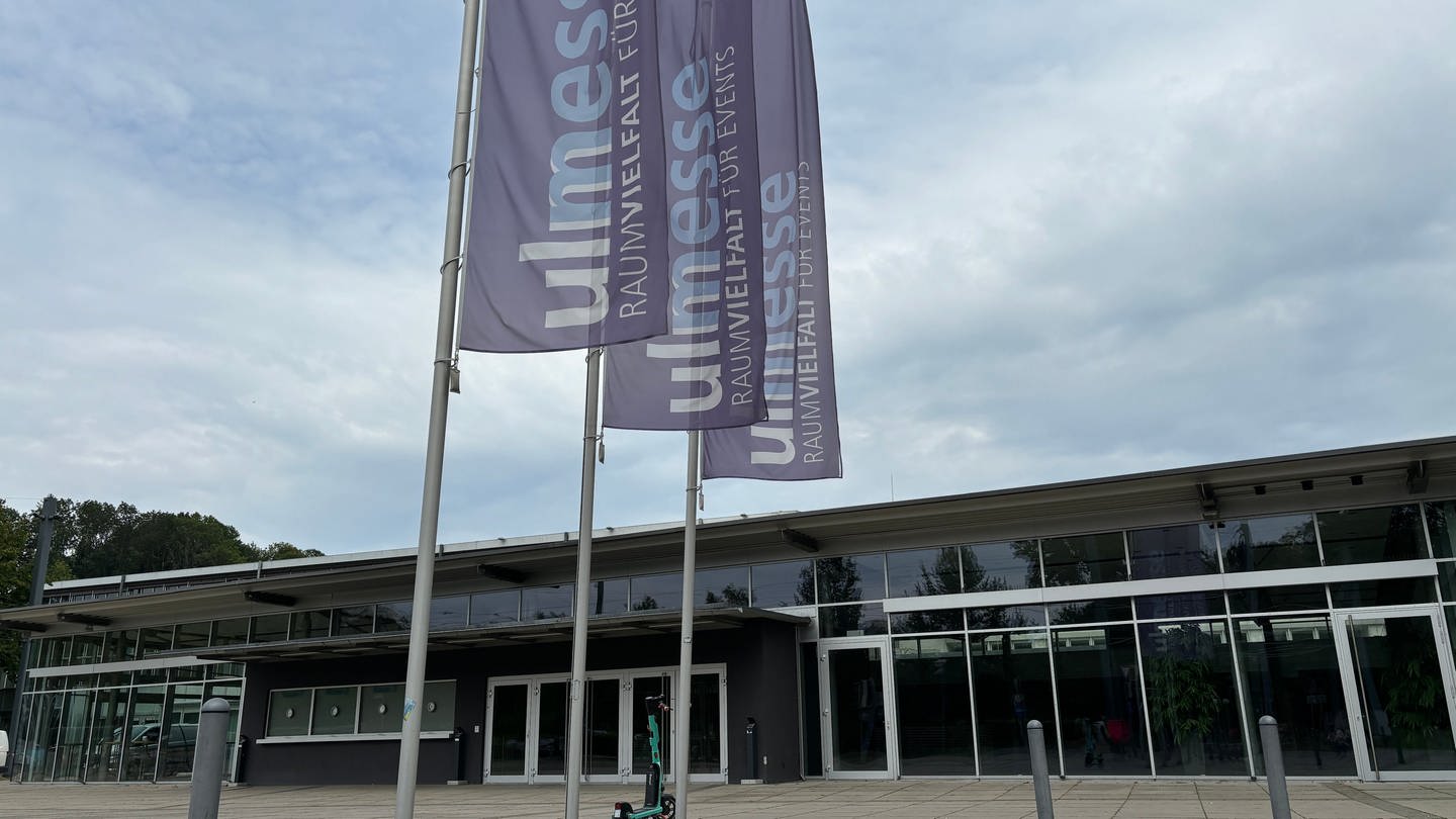 Der Eingang der Ulm Messe, ein flaches Gebäude mit mehreren Eingangstüren und Fahnen davor: Hier soll der Landesparteitag der AfD im Herbst stattfinden.