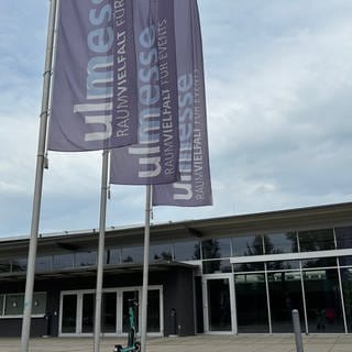 Der Eingang der Ulm Messe, ein flaches Gebäude mit mehreren Eingangstüren und Fahnen davor: Hier soll der Landesparteitag der AfD im Herbst stattfinden.