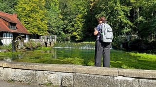 Eine Frau schaut auf das Wehr bei der Hammerschmiede am Blautopf in Blaubeuren. Die Touristenattraktion ist für Jahre wegen umfangreicher Umbauten gesperrt, ein direkter Blick auf die Karstquelle nicht möglich. Nun soll eine Besucherplattform gebaut werden.