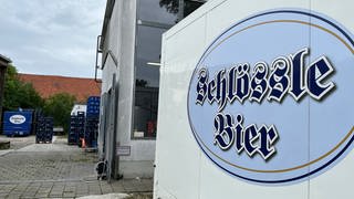 Ein Gebäude mit dem Schild der Gaststätte Schlössle und Bierkisten im Hintergrund: Die Brauerei des Schlössle in Neu-Ulm stellt den Betrieb ein