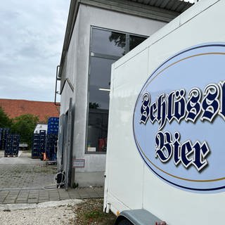 Ein Gebäude mit dem Schild der Gaststätte Schlössle und Bierkisten im Hintergrund: Die Brauerei des Schlössle in Neu-Ulm stellt den Betrieb ein