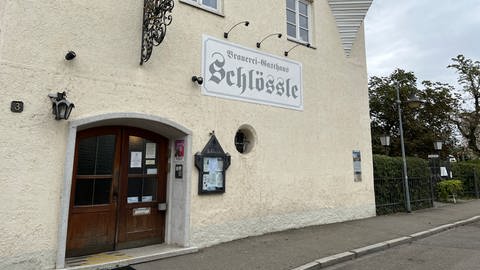 Ein Gebäude mit dem Schild der Gaststätte Schlössle und Bierkisten im Hintergrund: Die Brauerei des Schlössle in Neu-Ulm stellt den Betrieb ein