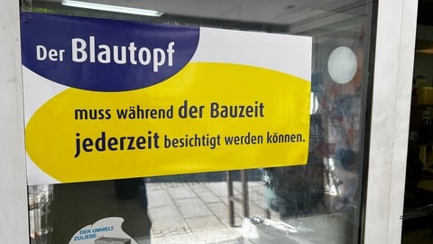 "Der Blautopf muss während der Bauzeit jederzeit besichtigt werden können." Dieser Text steht auf einem Plakat in einem Schaufenster in Blaubeuren.