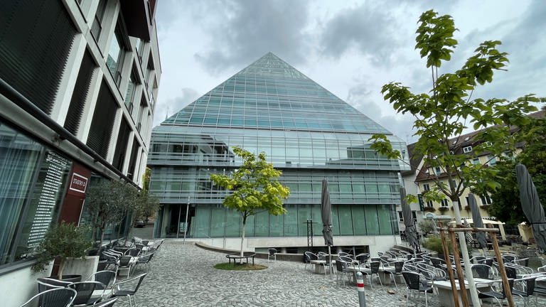 In der gläsernen Pyramide in der Ulmer Innenstadt spiegeln sich Bäume und Gebäude wider.