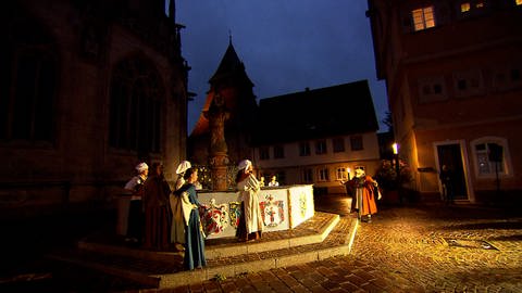 Mehrere Darsteller in einer Szene vor dem Münster in Schwäbisch Gmünd. Der Himmel ist fast komplett dunkel, der Regen hat aufgehört. Das wechselhafte Wetter hat die rund 50 Zuschauer nicht davon abgehalten, den ganzen Mix Musical, Theater und Stadtführung mitzumachen. 