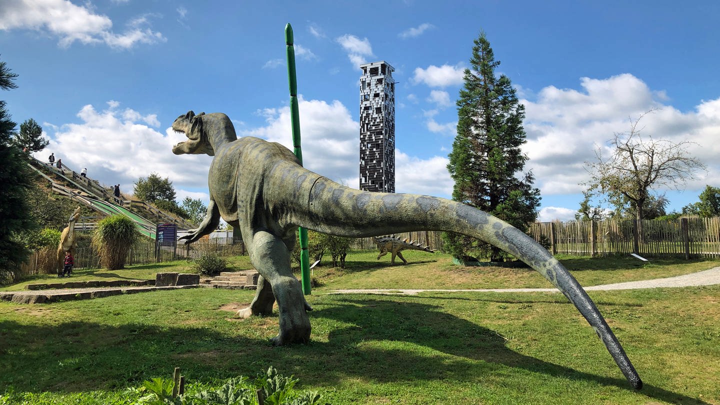 Ein T-Rex auf einer Wiese scheint mit seinem aufgerissenen Maul eine Wolke vom Himmel zu pflücken. Und tatsächlich: Der Himmel über dem Dinosaurierpark im Himmelsgarten in Schwäbisch Gmünd ist schon deutlich blauer als in den vergangenen Tagen.