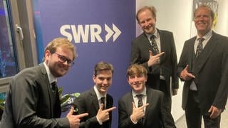 Die St. Georgs Chorknaben - Männer in schwarzen Anzügen und Krawatten posen im SWR Studio Ulm