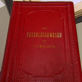 "Das Feuerlöschwesen": Buch von Conrad Dietrich Magirus mit rotem Umschlag. 