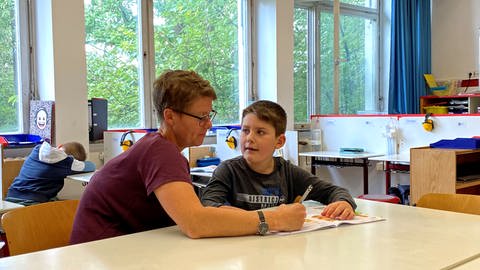 Eine Lehrerin sitzt mit einem Kind an einem Tisch und übt Deutsch. Das Ziel der Hans-Zulliger-Schule: Schülerinnen und Schüler auf den Besuch einer Regelschule vorbereiten.