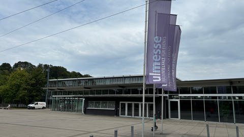 Der Eingang der Ulm Messe, ein flaches Gebäude mit mehreren Eingangstüren und Fahnen davor: In der Donauhalle der Ulm Messe will die AfD die Kandidatinnen und Kandidaten für die nächste Bundestagswahl bestimmen. Vor der Messe haben Organisationen wie auch Fraktionen des Gemeinderates in Ulm zu Gegendemos aufgerufen. Polizei und Stadt haben ein Sicherheitskonzept veröffentlicht.