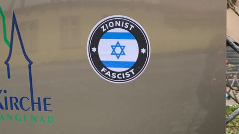 Ein Aufkleber, auf dem "Faschist" und "Zionist" steht. Dazwischen die Flagge Israels. Er wurde in der Nähe des Wohnhauses des Pfarrers Ralf Sedlak in Langenau entdeckt.