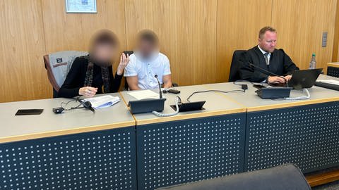 Der 32-jährige Verurteilte (unkenntlich gemacht) sitzt neben seiner Dolmetscherin in einem Saal im Landgericht Ulm. Er wurde für einen Raub in Blaustein verurteilt. Neben ihm sein Verteidiger.