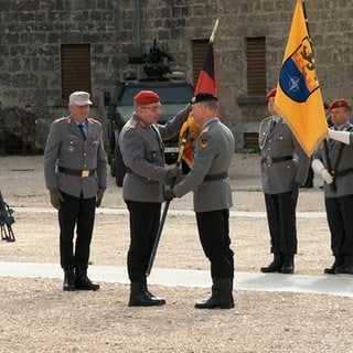 Generalleutnant Kai Ronald Rohrschneider nimmt bei einer Zeremonie im Innenhof der Ulmer Wilhelmsburg, die Fahne des Multinationalen Kommandos Operationale Führung entgegen. Sie wird ihm gereicht vom Generalinspekteur der Bundeswehr, Carsten Breuer, der sie von Generalleutnant Alexander Sollfrank bekommen hatte.