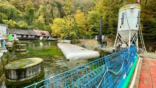 Baugeräte, Rohre, ein blauer Zaun und im Hintergrund die Hammerschmiede am Blautopf: Mit einem offiziellen Spatenstich hat am MIttwochnachmittag die Sanierung des Blautopf-Areals in Blaubeuren begonnen.