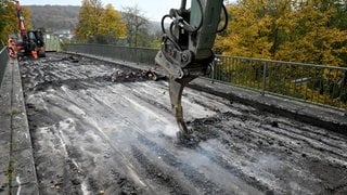 Bagger auf einer Brücke, Schutz für Gleise durch Styropormatten: Der Abriss einer maroden Brücke bei Blaustein hat schon am Samstag begonnen. So kann die Bahnstrecke Ulm-Blaubeuren womöglich früher wieder freigegeben werden. 