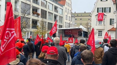 Streikende Menschen mit Fahnen und Plaketen, im Hintergrund eine Bühne: Die IG Metall hatte in Ulm zu einer Kundgebung aufgerufen. Etwa 150 Menschen kamen. 