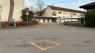 Vor der Schule ist ein orangenes Quadrat aufgemalt. Hier soll ein ehemaliger Schüler der Sägefeld-Schule in Ulm-Wiblingen einen Lehrer niedergeschlagen und lebensbedrohlich verletzt haben. 