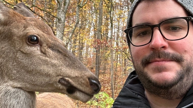 Selfie von SWR Reporter Dennis Bechtold mit Hirschkuh Gretl links im Bild. Sie nimmt den Reporter genau unter die Lupe, der sie im Wildpark Heidenheim besucht hat.