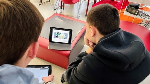 Auf ihren Tablets erarbeiten zwei Schüler in der Bibliothek der Kocherburgschule in Aalen-Unterkochen moderne Flugblätter in der Tradition der Weißen Rose, zu der auch Hans und Sophie Scholl gehörten. Darauf stehen Themen, die die Jugendlichen selbst bewegen - wie Falschinformation, Mobbing oder Frauenrechte.