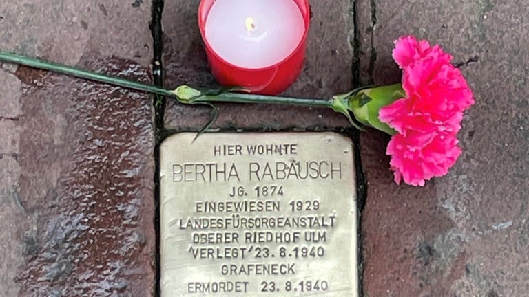 Ein frisch geputzter Stolperstein in Ulm. Eine Nelke und eine Kerze erinnern an die Richtspogromnacht am 9. November 1938. Eine Putzaktion 