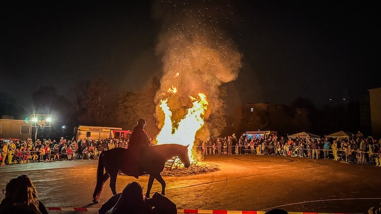 Sankt Martin reitet vor einem großen Feuer inmitten von Kindergartenkindern in Neu-Ulm.