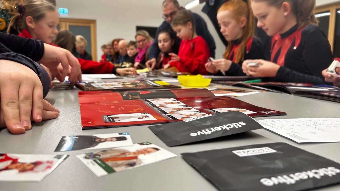 An einer großen Tafel im Ortsgemeinschaftshaus tauschen die Gmünderinnen und Gmünder ihre Bilder. Auf die Idee für das Sticker-Sammelalbum kamen die 1. Wexhainer Narrenzunft, einer Zunft in Schwäbisch Gmünd.