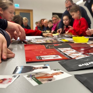 An einer großen Tafel im Ortsgemeinschaftshaus tauschen die Gmünderinnen und Gmünder ihre Bilder. Auf die Idee für das Sticker-Sammelalbum kamen die 1. Wexhainer Narrenzunft, einer Zunft in Schwäbisch Gmünd.