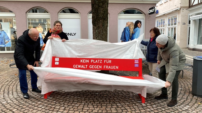 "Kein Platz für Gewalt an Frauen" steht auf der roten Bank. Rote Bänke stehen als Zeichen gegen Gewalt an Frauen unter anderem in Ellwangen und Schwäbisch Gmünd. Aalens Bürgermeister Bernd Schwarzendorfer, die SPD-Bundestagsabgeordnete Leni Breymaier, Rita Mager vom Kreisfrauenrat Ostalb und Aalens Oberbürgermeister Frederick Brütting (von links) haben am Donnerstag (21.11.) in Aalen die Bank enthüllt. 