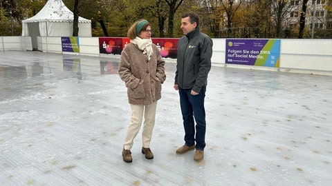 Karin Haisch von der Stadt Aalen und Igor Dimitrijoski stehen mitten auf der Fläche des Eisparks auf dem Bohlschulplatz und unterhalten sich. 