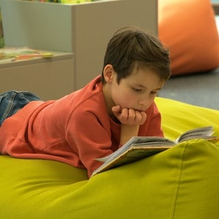 Ein Kind liest in einem Buch. Auf der Kinderbuchmesse in der Stadtbibliothek Ulm können die kleinen Gäste in rund 2.000 Neuerscheinungen schmökern.