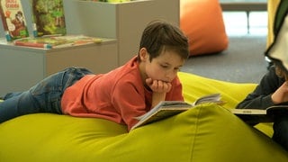 Ein Kind liest in einem Buch. Auf der Kinderbuchmesse in der Stadtbibliothek Ulm können die kleinen Gäste in rund 2.000 Neuerscheinungen schmökern.