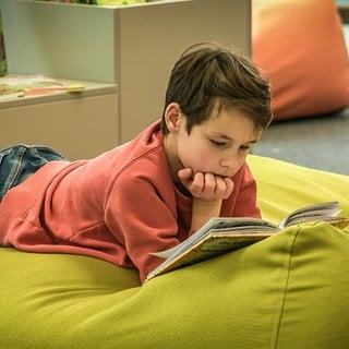 Ein Kind liest in einem Buch. Auf der Kinderbuchmesse in der Stadtbibliothek Ulm können die kleinen Gäste in rund 2.000 Neuerscheinungen schmökern.