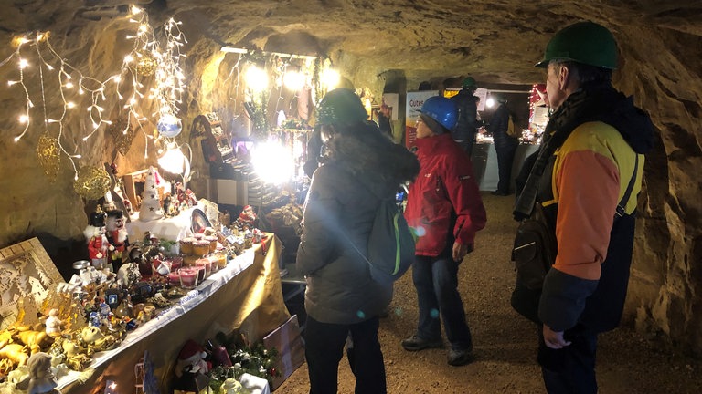 Im Tiefen Stolle, dem Besucherbergwerk in Aalen, leuchtet es taghell, Christkind und Nikolaus sind dort, Weihnachtsbäume und viele Stände. Der Weihnachtsmarkt hat begonnen. Auch wenn man fast vergessen kann, unter Tage zu sein, die Besucherinnen und Besucher müssen sicherheitshalber einen Helm tragen.