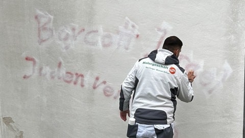 Maler entfernen die Schmierereien in Langenau. Unbekannte hatten am Wochenende judenfeindliche Parolen an die Wände von Kirche und Rathaus geschmiert. 