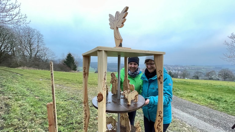 Zwei Frauen vor einer Holzkrippe im Freien: Der Krippenweg rund um den Stuifen bei Waldstetten-Wißgoldingen (Ostalbkreis) ist eröffnet worden. Organisatorinnen sind Beate Kornau und Anja Barth. 95 Krippen sind es in diesem Jahr - gemacht und bereitgestellt von Vereinen und Privatpersonen aus der Umgebung. (14.11.)