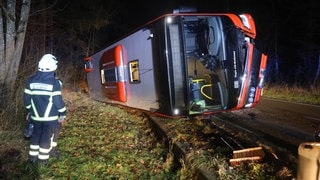 Der umgekippte Linienbus liegt auf der Straße zwischen Blaubeuren und Blaustein. Davor steht ein Feuerwehrmann. 