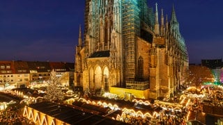 Der hell erleuchtete Weihnachtsmarkt in Ulm bei Nacht - Organisator und Standbetreiber ziehen eine positive Bilanz für 2024. nach dem Anschlag in Magdeburg wurden die Sicherheitsvorkehrungen aber nochmals erhöht. 