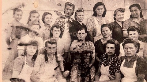 Schwarz-Weiß-Foto aus einem sowjetischen Lager zeigt junge Frauen in Schürzen mit ernstem Blicke Ulm gedenkt - DZM Ulm gedenkt der Deportation vor 80 Jahren.