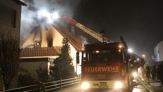 Feuerwehrleute löschen über eine Drehleiter Flammen in einem Einfamilienhaus. Bei einem Brand im Ulmer Stadtteil Jungingen ist ein Mensch ums Leben gekommen. Die Feuerwehr barg einen Toten. 